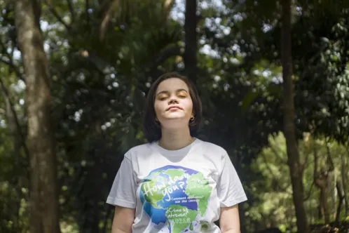 La jeune Kyara, âgée de 16 ans, se tient dans la forêt du Costa Rica, les yeux fermés, respirant la nature environnante.