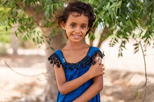 In Yemen, a 7-year-old girl smiles at the camera while holding cotton on her upper arm after being vaccinated.