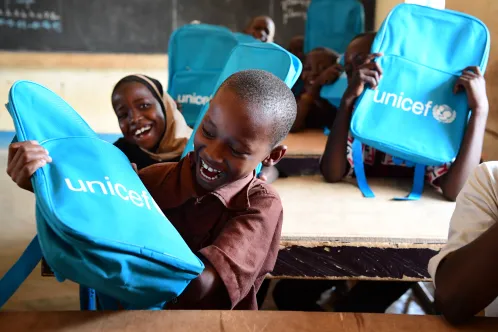 In Niger, excited schoolchildren smile and laugh at their desks after receiving UNICEF school backpacks.