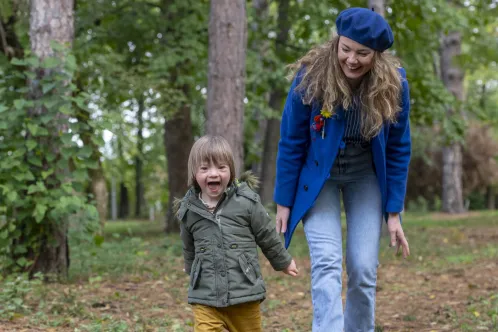 A mother plays with her son with down syndrome in a park.