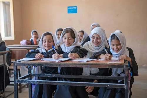  A group of girls writing at a desk.