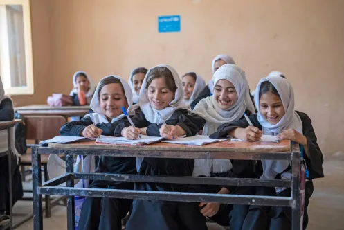 A group of girls writing at a desk.