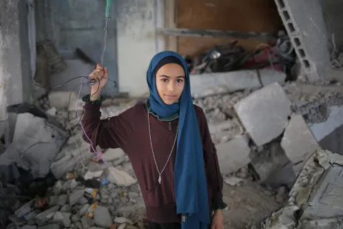 12-year-old girl stands inside her destroyed house in Rafah, southern the Gaza Strip.