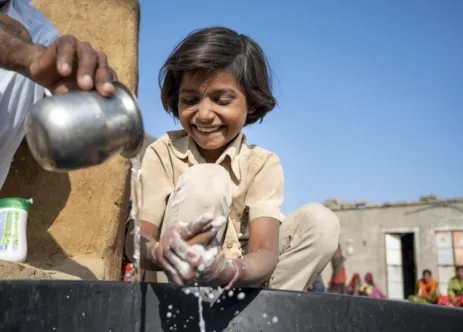 Un membre d’une collectivité aide une enfant à se laver les mains avec du savon au Bangladesh.