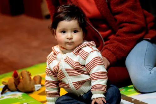 A mother and her child sitting on the floor reading a picture book.