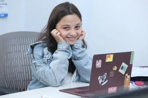 Eva, âgée de 12 ans, est assise à son bureau et tente de résoudre un jeu mathématique sur son ordinateur portable.