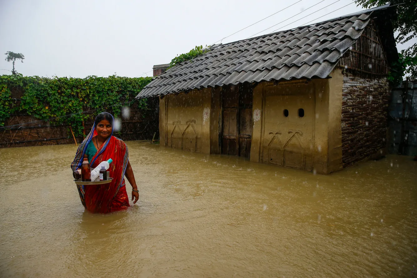 A woman is seen outside her flood-inundated home in Saptari District.