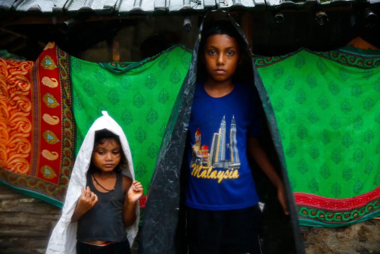 Two girls use plastic sheets as makeshift rain cover in Saptari District.