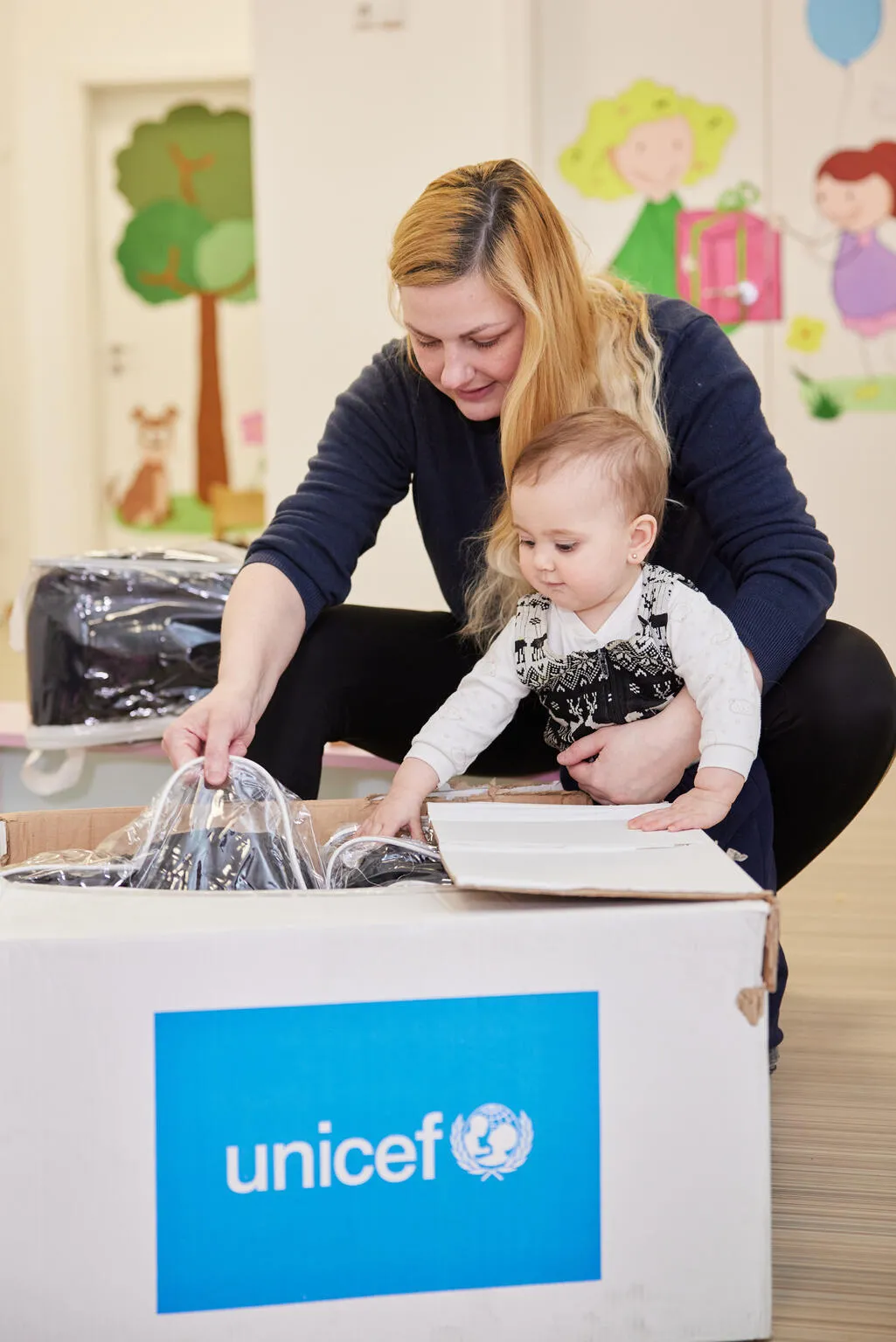 Une mère et un enfant ouvrent une boîte de l’UNICEF