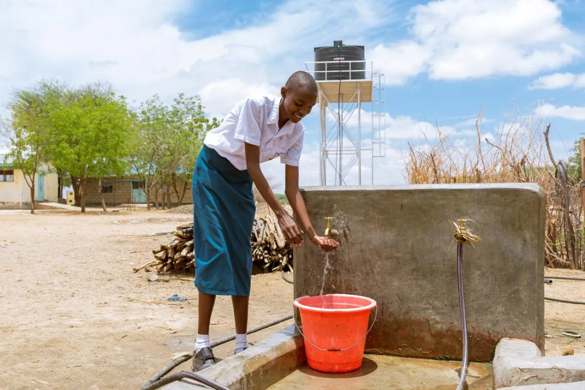 Sharlyne fills a bucket with safe water at Nabulon Primary School.
