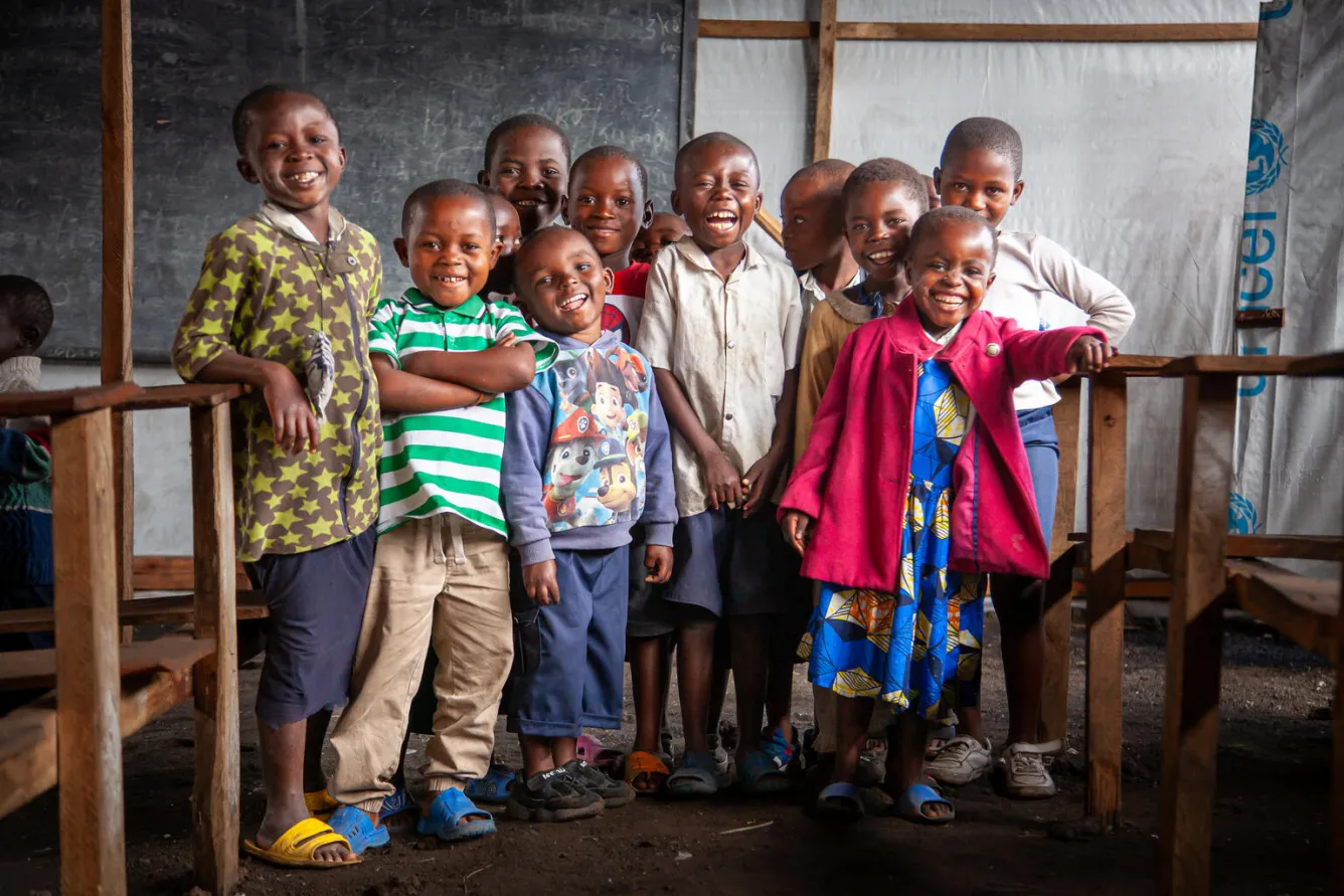 Des enfants sourient à l’objectif dans un espace d’apprentissage temporaire soutenu par l’UNICEF en République démocratique du Congo.