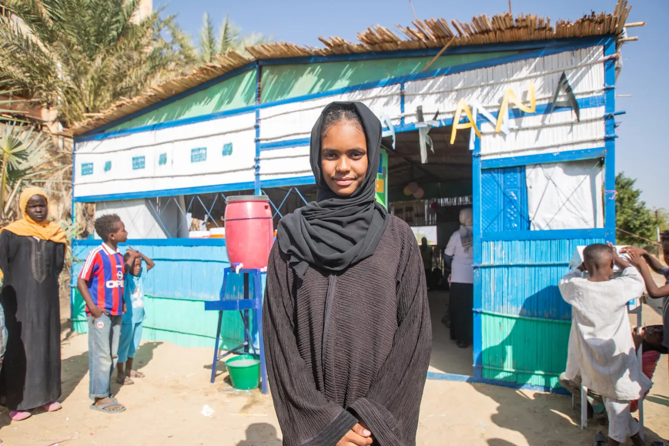 Au Soudan, la jeune Shaimaa, âgée de 14 ans, se tient devant un Makanna, un espace sûr et adapté aux enfants, soutenu par l’UNICEF.