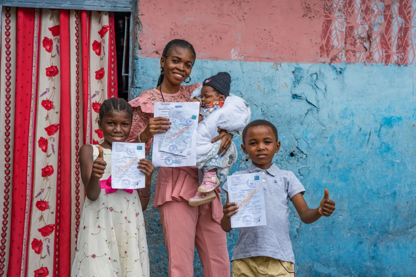 À Kinshasa, en République démocratique du Congo, Noëlla brandit l’acte de naissance de son nouveau-né, tandis que ses deux autres enfants brandissent le leur.