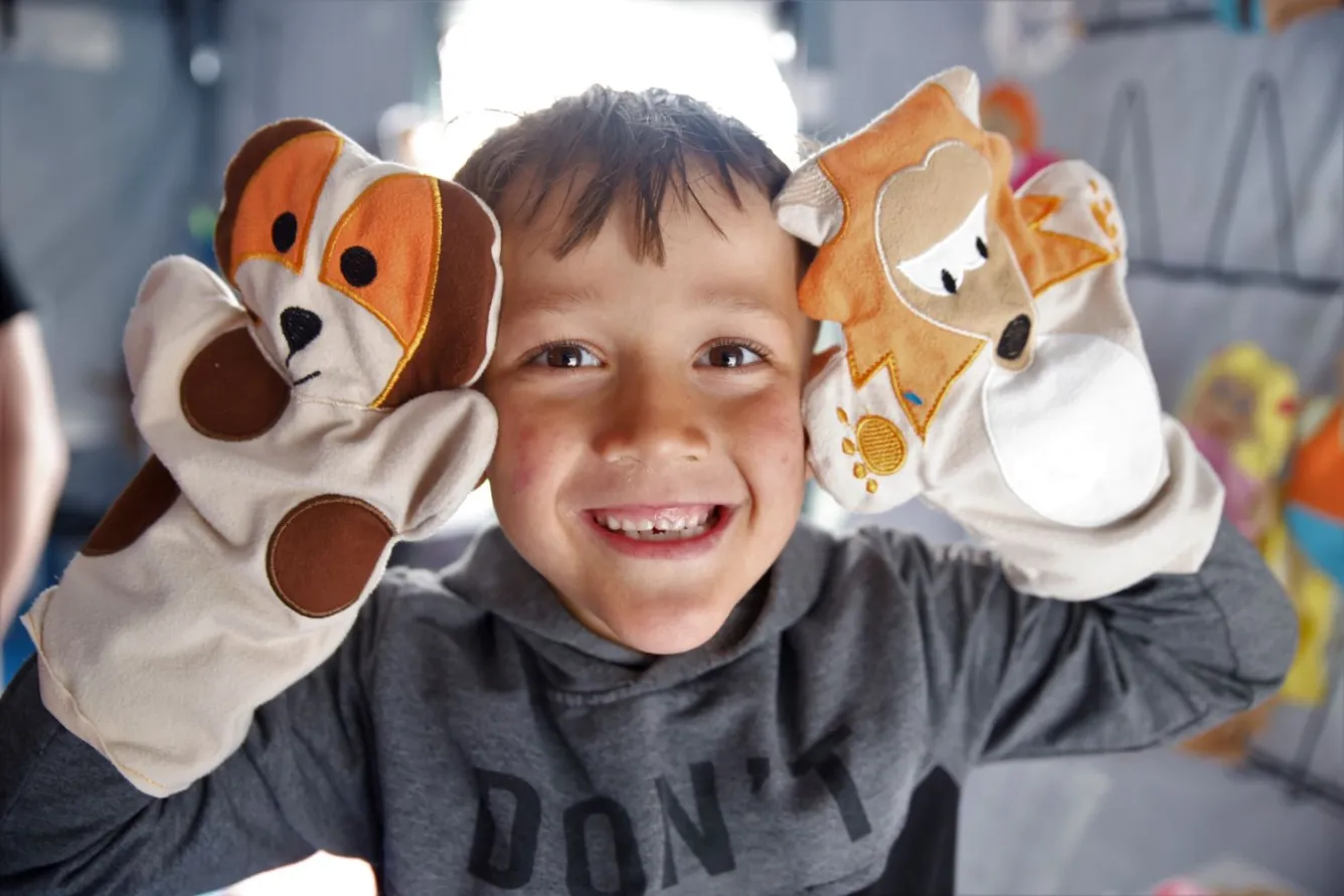 A boy plays with puppets at a temporary shelter in Hatay, Türkiye.