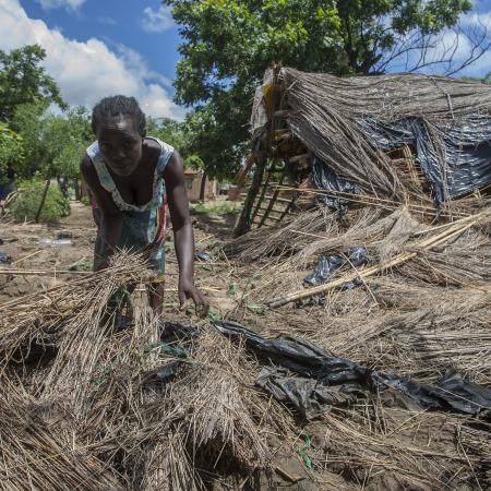 A woman searches through her destroyed home.