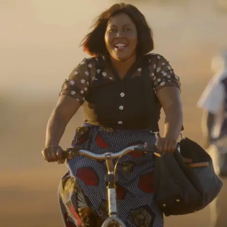 A woman with a book bag rides a bicycle down a street
