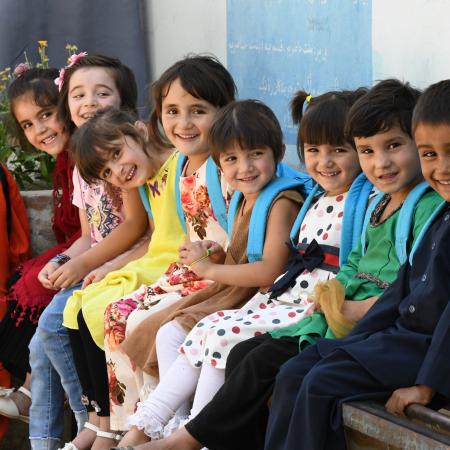 Un groupe d'enfants dans une cour de récréation dans le Nord de l'Afghanistan portant leurs nouveaux sacs à dos UNICEF.