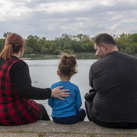 A family sits on a riverbank in Serbia.