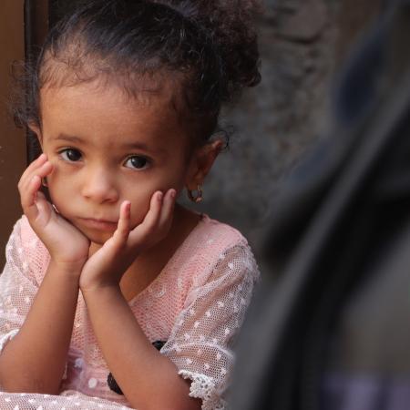 A young girl waits to receive life-saving supplies in Yemen.