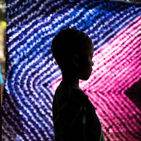 Une jeune fille pose devant un rideau vibrant et coloré