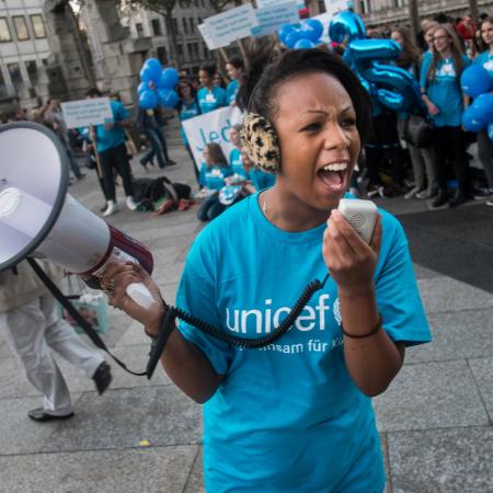 Une jeune femme entourée d’autres manifestants crie dans un mégaphone.