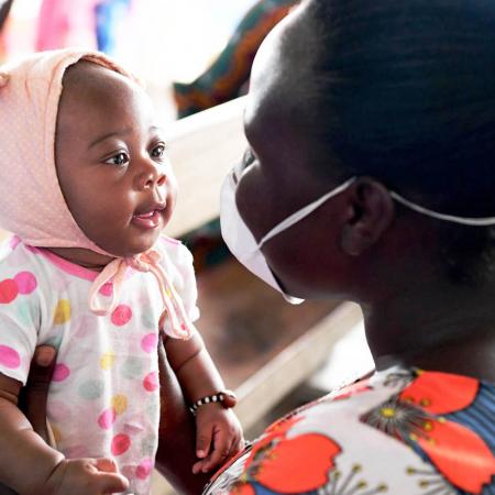 Amusée par le visage masqué de sa mère, Christelle, 3 mois, attend d’être vaccinée dans un centre de santé près d’Abidjan, en Côte d’Ivoire. 