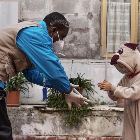 A UNICEF Italy staff member demonstrates handwashing to a young migrant girl.