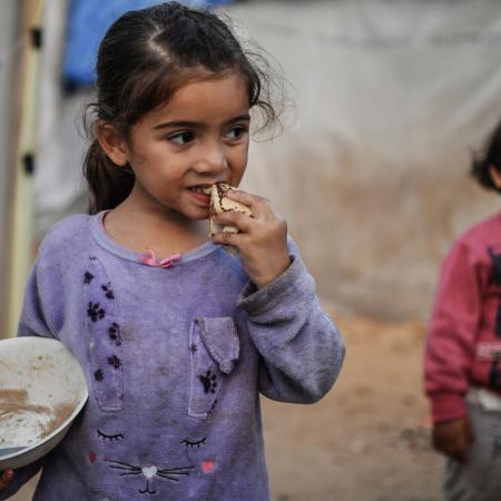 Israa eats a piece of bread in Khan Younis city.