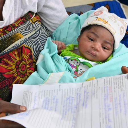 En Côte d’Ivoire, un bébé dort alors que sa mère tient son acte de naissance. 