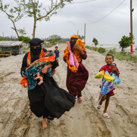 Inhabitants from the village of Panjupara are walking towards the shelter with their children and valuable household items during the rainfall in Kuakata, ahead of cyclone Remal's landfall in Bangladesh on May 26, 2024.
