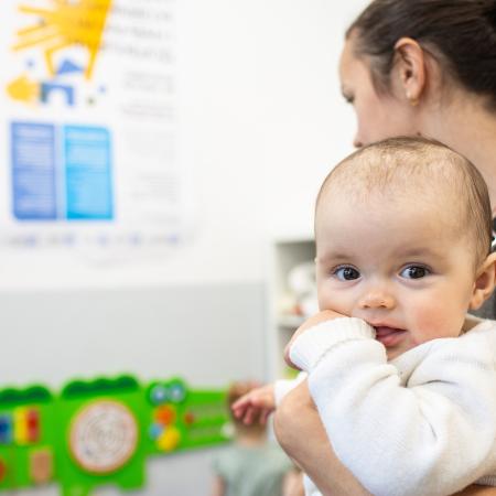 A mother lovingly holds her baby in a warmly lit room, showcasing a tender moment between them.