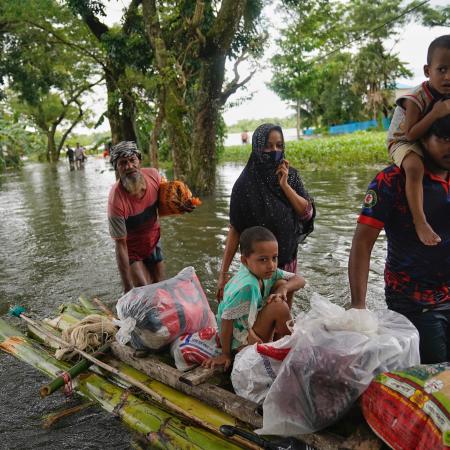 People travelling through the flood water on a make-shift raft, in search of shelter, in Feni.