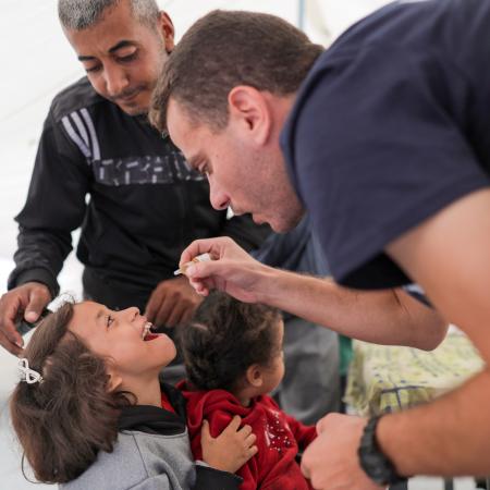 A health worker administers polio vaccine to a child in Gaza