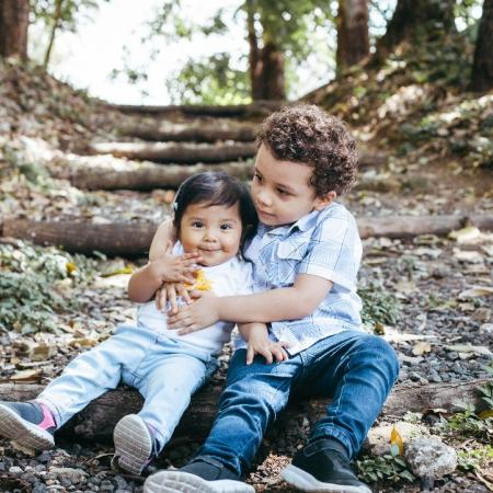 Two children are sitting together on the ground.