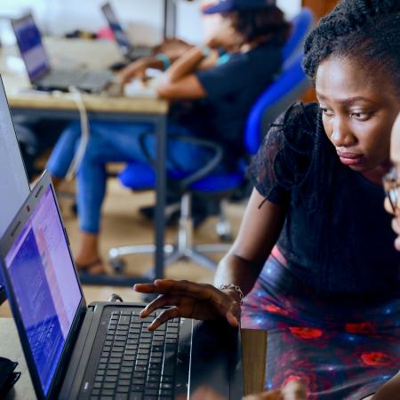 a man and a woman work at a computer which is showing code.